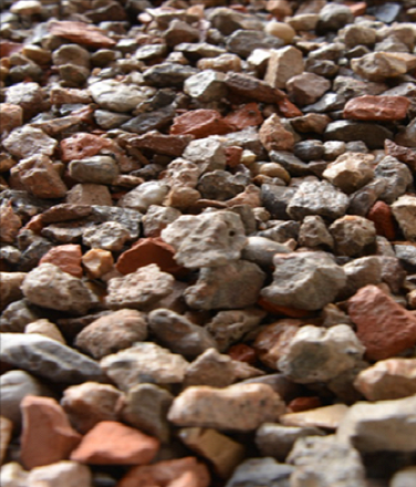 Nahaufnahme von Bauschutt: Verschiedene, grobe Steine und Ziegelstücke liegen gemischt auf einem Haufen. Die Farben reichen von Grau bis Rotbraun.

                          